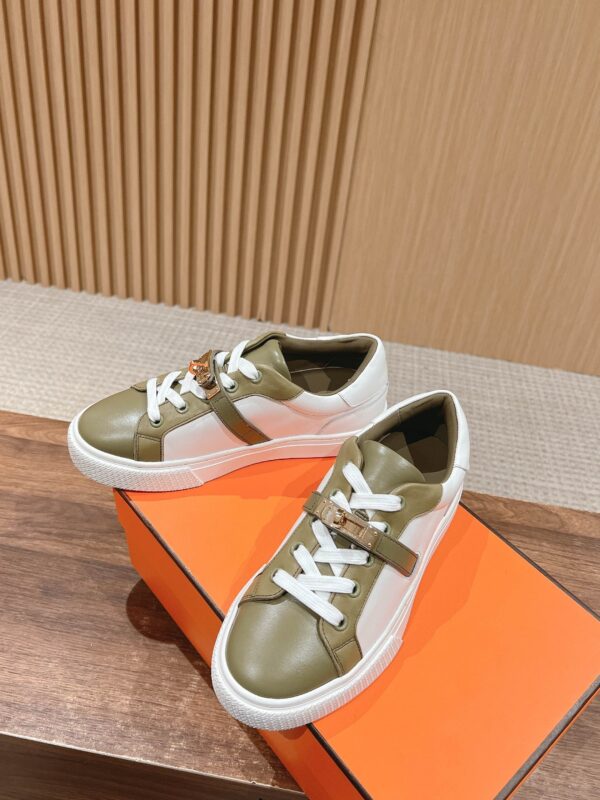 Sneakers green e bianco moderne, stile sportivo, su superficie in legno con scatola arancione elegante.