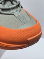 Sneaker moderna verde e arancione, stile sportivo, design resistente e traspirante.