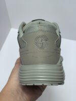 Sneaker grigia minimalista con logo circolare, suola spessa e design elegante per comfort e stile.