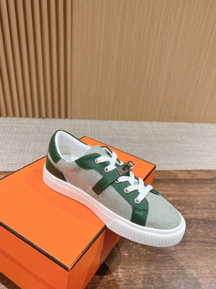 Sneaker casual grigia con dettagli verdi su scatola arancione, stile moderno e versatile.