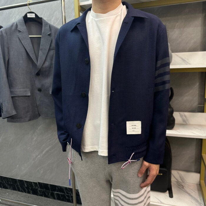 Stiloso uomo in boutique con camicia navy, t-shirt bianca e pantaloni grigi casual