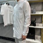 Moda uomo casual con camicia bianca, dettagli colorati e stile moderno in boutique elegante.