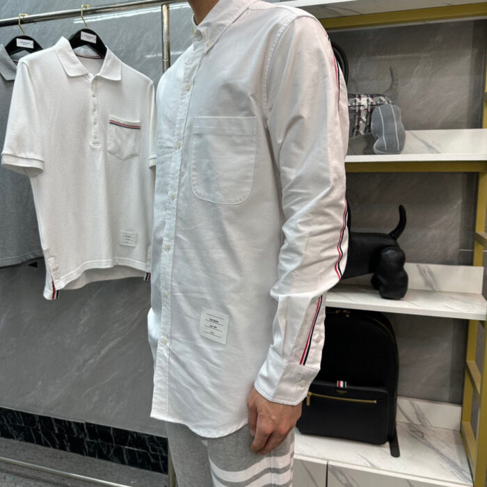 Moda uomo casual con camicia bianca, dettagli colorati e stile moderno in boutique elegante.