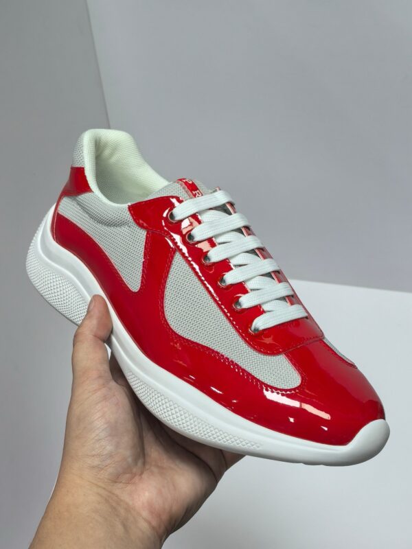 Sneaker moderna rossa e grigia, design sportivo elegante, in mano, stile casual e alla moda.