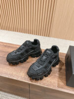 Sneakers nere robuste e moderne con suola chunky, su sfondo di legno chiaro elegante.