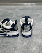 Sneaker navy e bianco con logo stilizzato, design moderno e suola resistente, stile casual e sportivo.