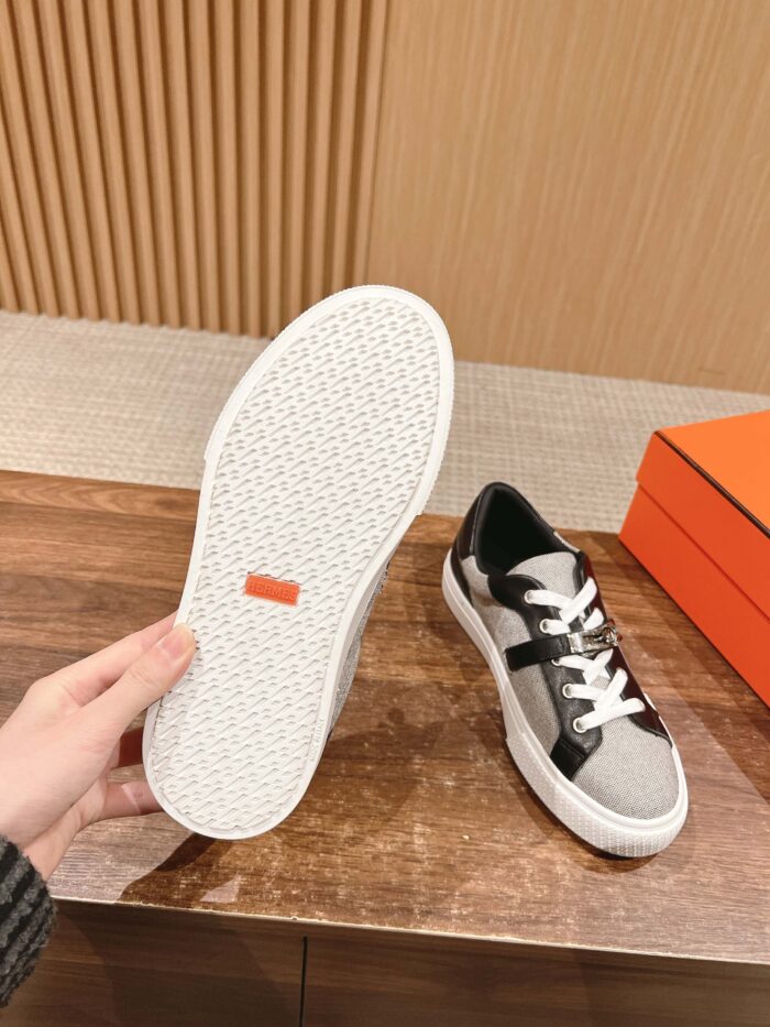 Sneaker moderna in nero e grigio con suola antiscivolo e logo arancione elegante.
