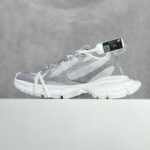 Sneaker bianca e grigia leggera con design moderno, suola chunky e dettaglio colorato allegro.
