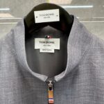 Giacca Thom Browne con colletto alto, zip elegante e dettagli iconici in stile moderno e sofisticato.