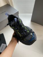 Scarpa da corsa moderna nero, blu e verde neon, design ergonomico e materiali traspiranti.