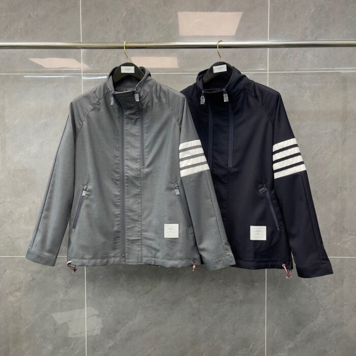 Giacche sportive moderne grigia e navy con zip, tasche e dettagli a strisce bianche.