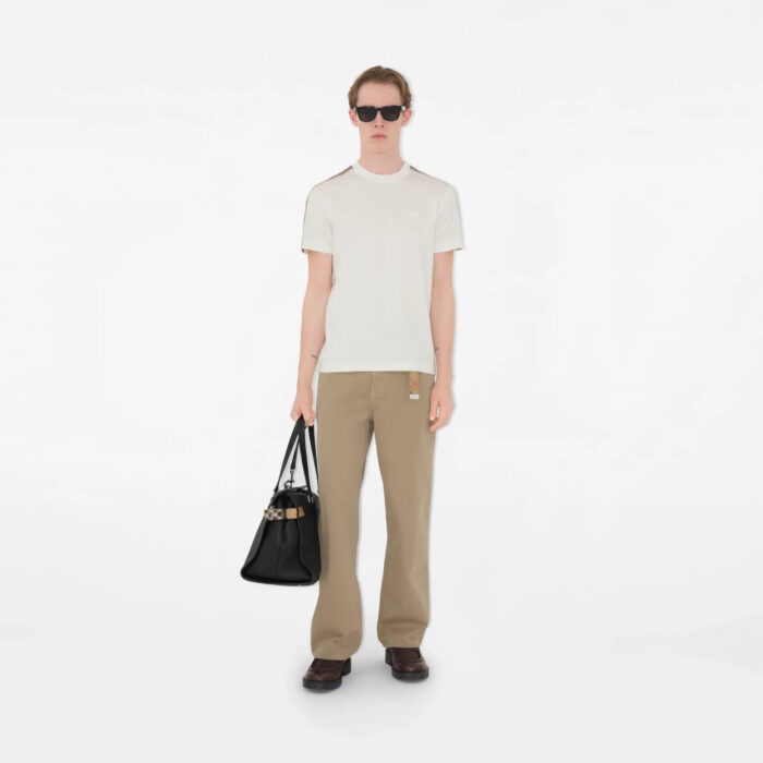 Look elegante e casual con pantaloni beige, maglietta aderente, occhiali scuri e borsa nera.