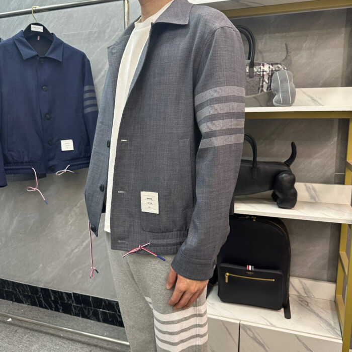Look casual edgy con giacca grigia e jogger moderni in store di moda contemporanea.