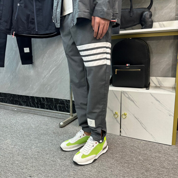Persona con jogger grigi a strisce e sneakers colorate in ambiente moderno e minimalista.