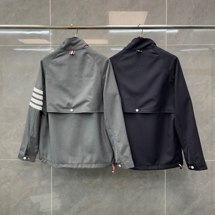 Giacche moderne casual e sportiva con dettagli flap, in grigio e nero, sullo sfondo a piastrelle.