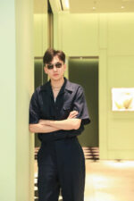 Giovane uomo alla moda con abbigliamento navy e occhiali in ambientazione moderna raffinata.