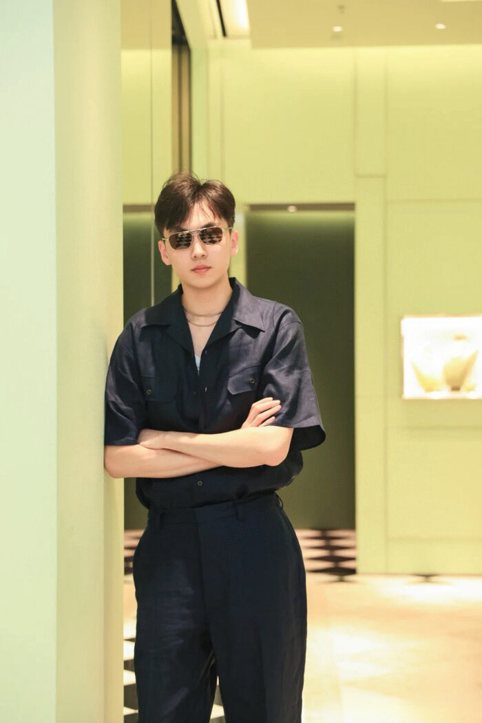 Giovane uomo alla moda con abbigliamento navy e occhiali in ambientazione moderna raffinata.