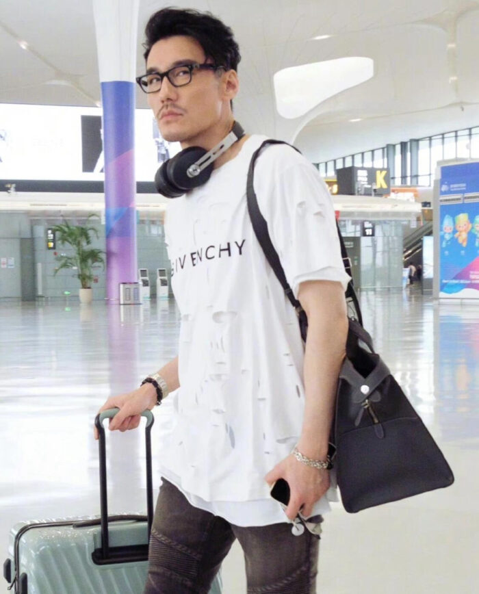 Viaggiatore moderno in aeroporto con stile streetwear Givenchy e accessori eleganti.