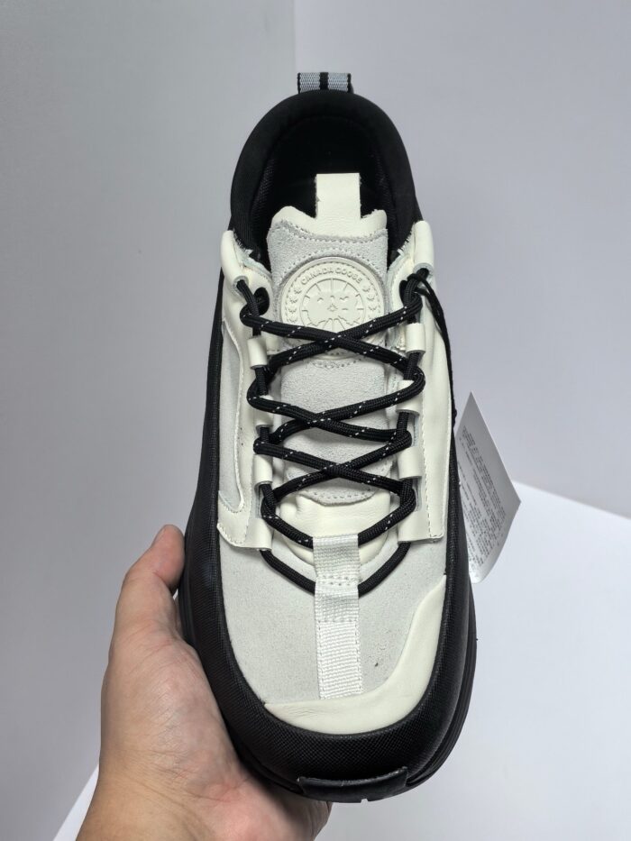 Sneaker bianca e nera trendy, comfort e stile, in mano con design moderno e versatile.