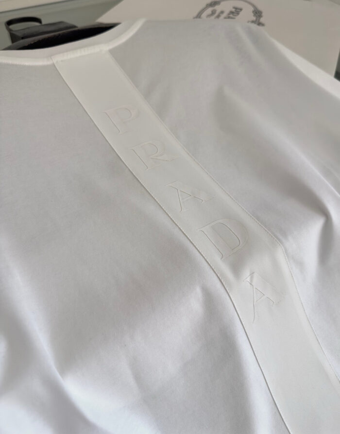 Maglietta bianca minimalista con dettaglio embossato sul retro e finiture di alta qualità.