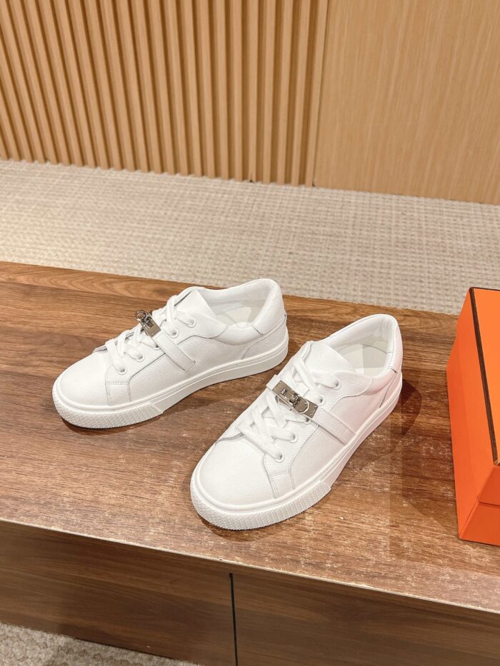 Sneakers bianche moda con suola chunky e scatola arancione in ambiente elegante e minimalista.