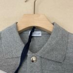 Poloshirt Moncler grigio chiaro in cotone con bottoni metallici e etichetta elegante.