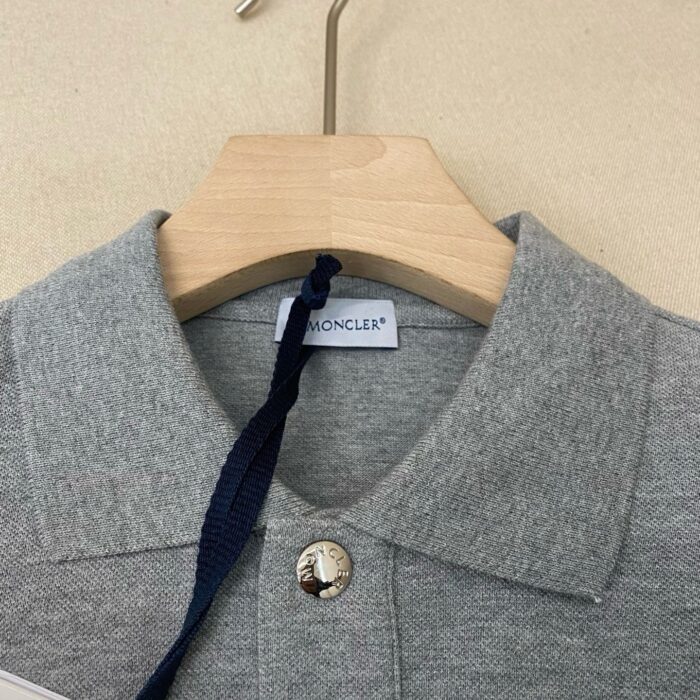 Poloshirt Moncler grigio chiaro in cotone con bottoni metallici e etichetta elegante.