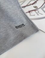 Logo Moncler su abbigliamento elegante con occhiali, stile di lusso e raffinatezza.