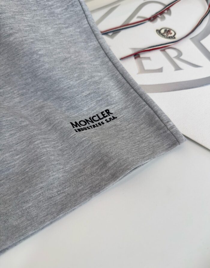 Logo Moncler su abbigliamento elegante con occhiali, stile di lusso e raffinatezza.