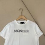 Maglietta bianca Moncler logo moderna, stile casual, tessuto di alta qualità su appendiabiti.