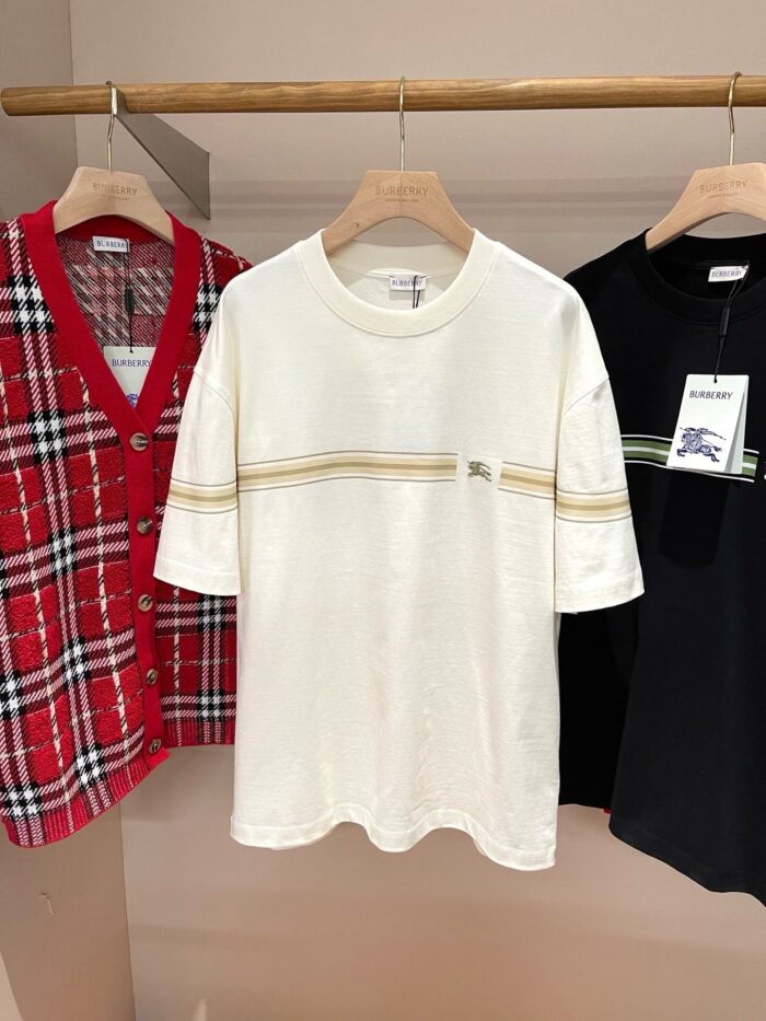 Esposizione di abbigliamento con cardigan a quadri, t-shirt bianche e nere su gruccia in stile casual.