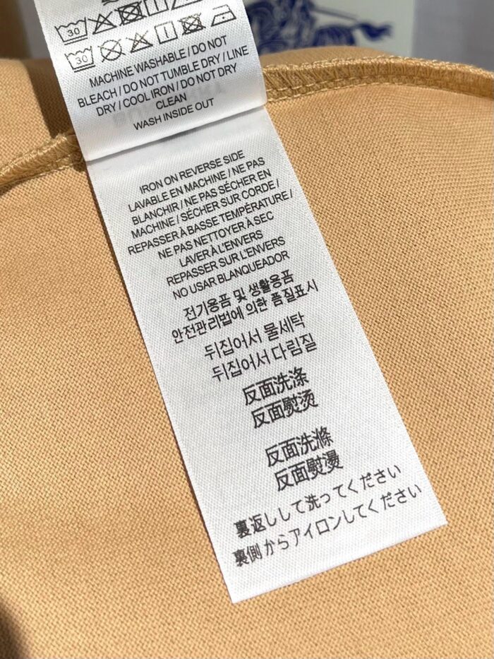 Etichetta di cura del vestito con istruzioni in più lingue e simboli di lavaggio.