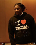 Uomo con felpa “I ❤️ Mariah” mostra passione musicale e stile casual in ambiente caldo.