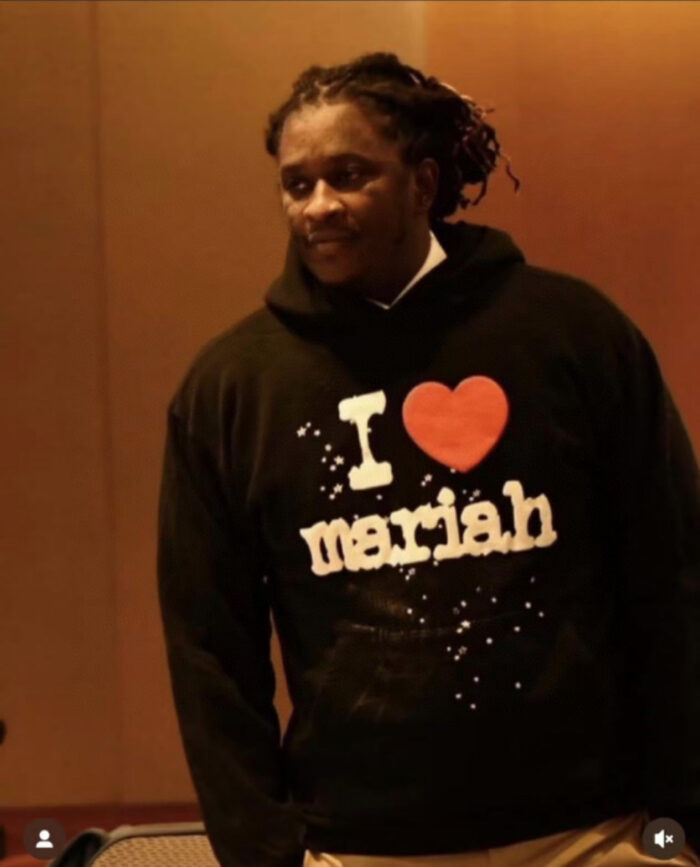 Uomo con felpa “I ❤️ Mariah” mostra passione musicale e stile casual in ambiente caldo.