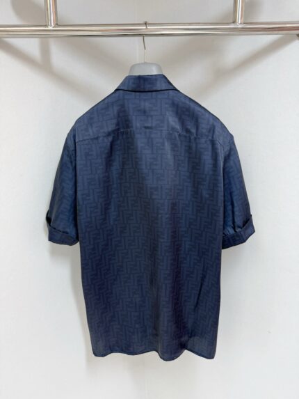 Camicia morbida blu navy con dettagli eleganti, maniche arrotolate, appesa su sfondo neutro elegante.
