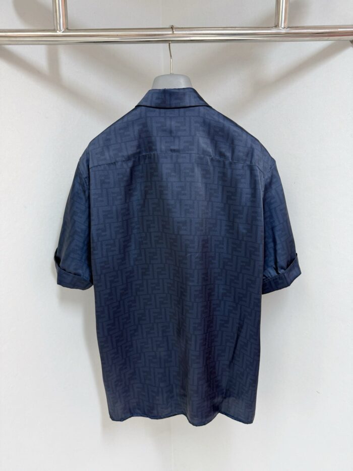 Camicia morbida blu navy con dettagli eleganti, maniche arrotolate, appesa su sfondo neutro elegante.