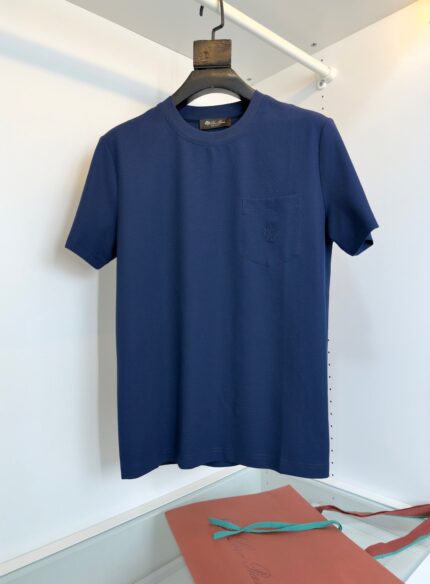 Maglietta navy blu casual e elegante su appendiabiti in legno con dettagli minimalisti.