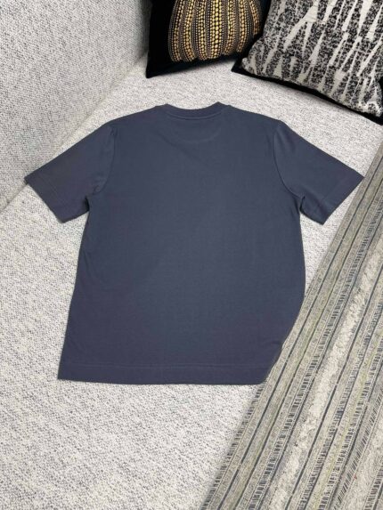 T-shirt casual navy su divano con cuscini decorativi, stile minimalista e comfort domestico.