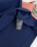 Dettagli in navy e corallo con etichetta di cura e tracolla azzurro chiaro.