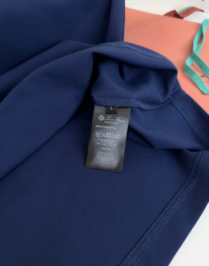 Dettagli in navy e corallo con etichetta di cura e tracolla azzurro chiaro.