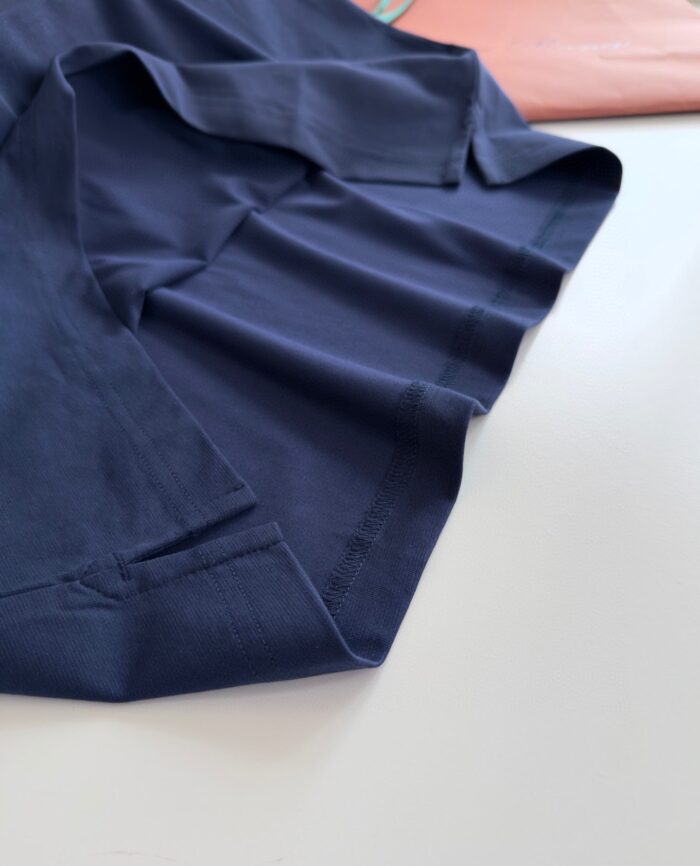 Dettaglio di camicia navy blu con colletto classico e contrasto rosa elegante.