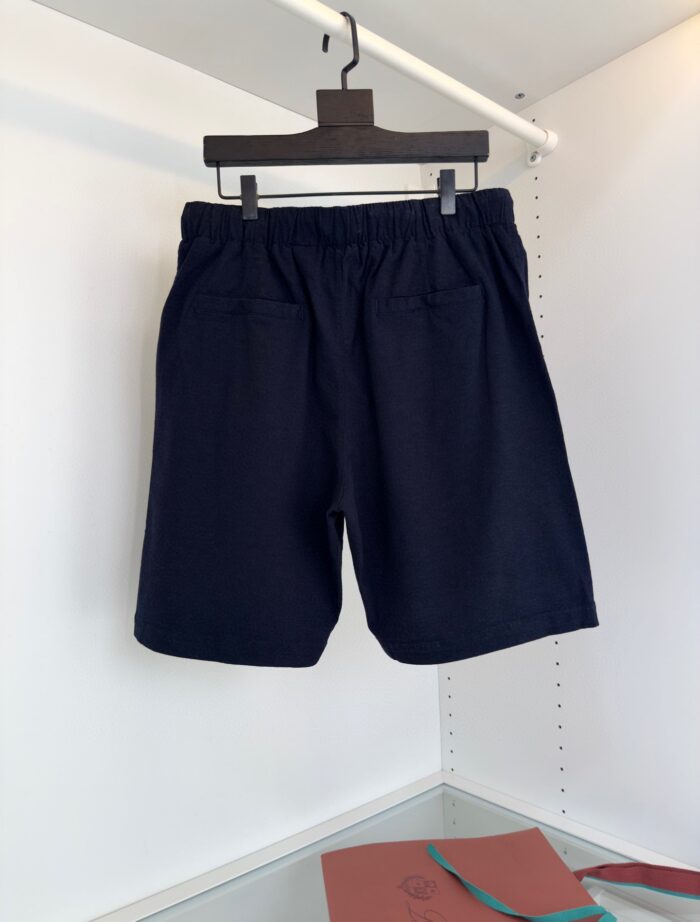 Pantaloncini navy elasticati casual da uomo con tasche, su appendiabiti nero, sfondo bianco semplice.