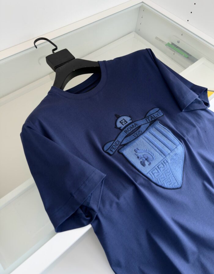 Maglietta navy blue con emblemma ricamato elegante, stile casual e versatile.
