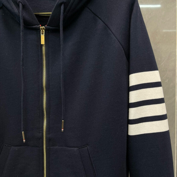 Felpa navy blu con strisce bianche, zip dorata e tasca frontale, stile sportivo e casual.