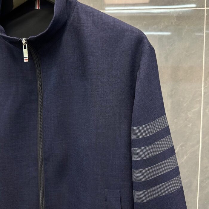 Giaccone navy blue moderno con dettagli a strisce, zip frontale e tasche pratiche.