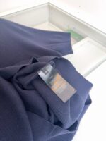 Maglione blu navy con etichetta di cura, tessuto morbido e stile versatile.