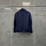 Giacchetto blu navy minimalista su sfondo grigio, stile casual e versatile.