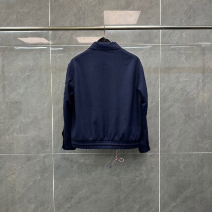Giacchetto blu navy minimalista su sfondo grigio, stile casual e versatile.