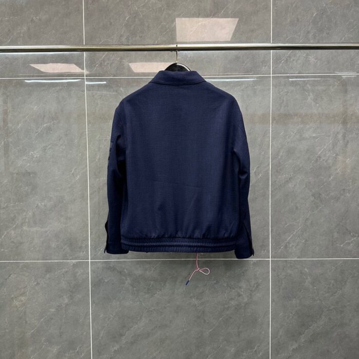 Giacchetto blu navy minimalista su sfondo grigio, stile casual e versatile.