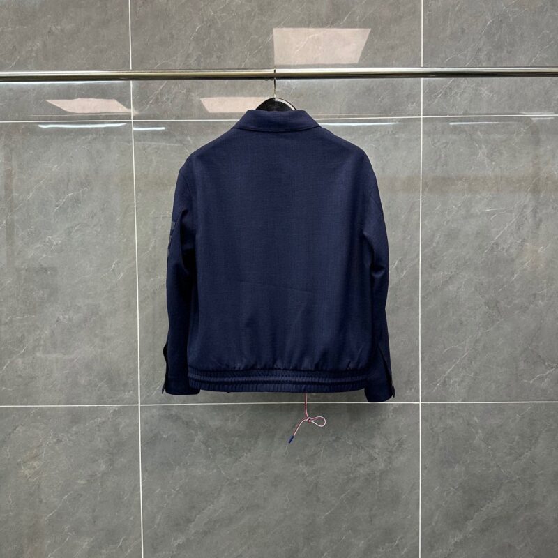 Giacchetto blu navy minimalista su sfondo grigio, stile casual e versatile.